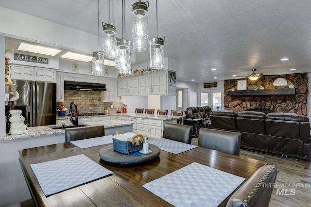 dining room featuring ceiling fan, sink, hardwood / wood-style floors, and a textured ceiling