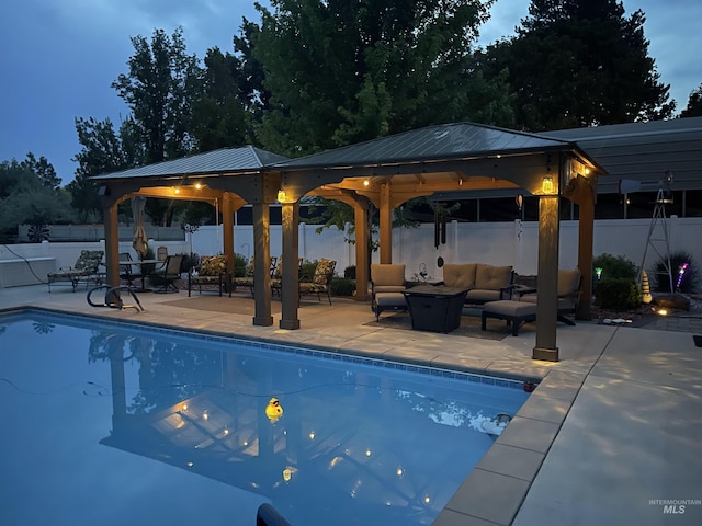 pool at dusk featuring a gazebo, an outdoor hangout area, and a patio