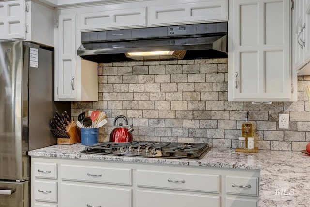 kitchen with stainless steel appliances, extractor fan, white cabinets, and decorative backsplash