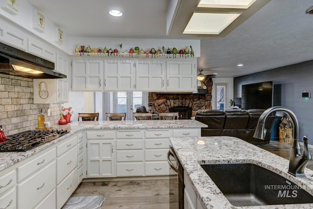 kitchen featuring sink, ceiling fan, black dishwasher, white cabinets, and stainless steel gas stovetop