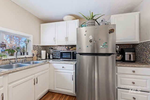 kitchen with sink, white cabinetry, light hardwood / wood-style flooring, appliances with stainless steel finishes, and backsplash