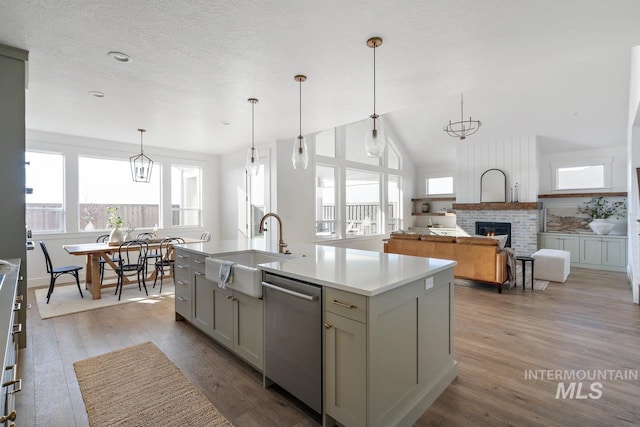 kitchen featuring gray cabinetry, stainless steel dishwasher, sink, light hardwood / wood-style flooring, and an island with sink