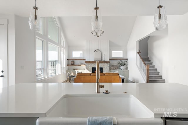 kitchen featuring hanging light fixtures, a brick fireplace, high vaulted ceiling, and light countertops