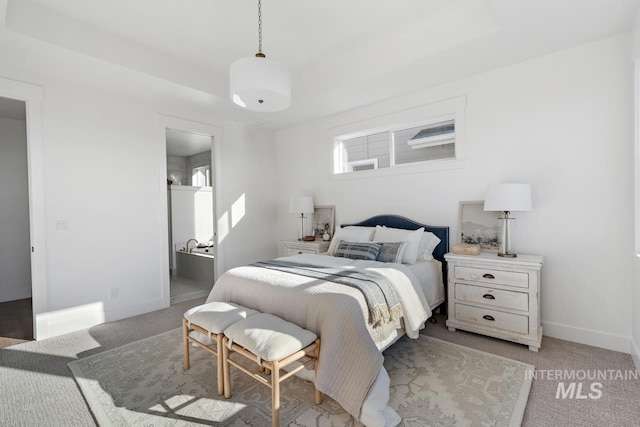 carpeted bedroom with a raised ceiling and baseboards