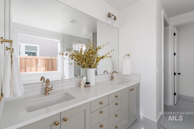 bathroom featuring visible vents, a sink, decorative backsplash, and double vanity