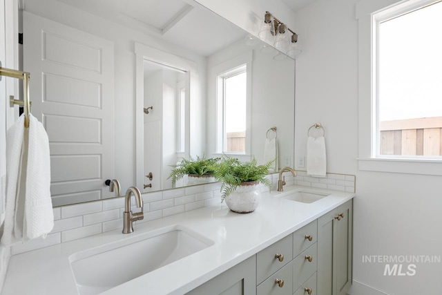 full bath with double vanity, plenty of natural light, and a sink