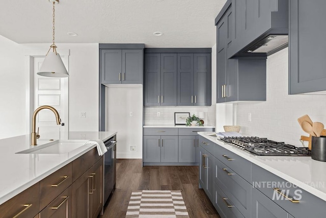 kitchen with appliances with stainless steel finishes, light countertops, a sink, and pendant lighting