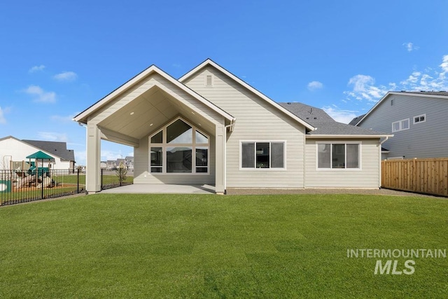 rear view of property with a playground, a lawn, a patio area, and fence