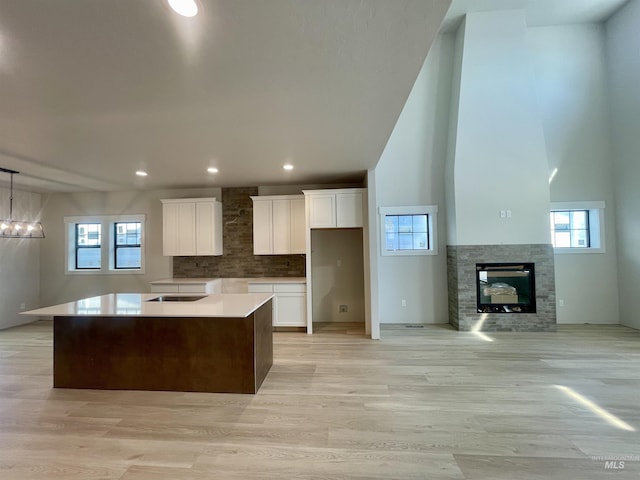 1640 E Cutgrass Ln, Eagle, ID 83616 - kitchen with white cabinets, decorative backsplash, a glass covered fireplace, a kitchen island, and black electric cooktop