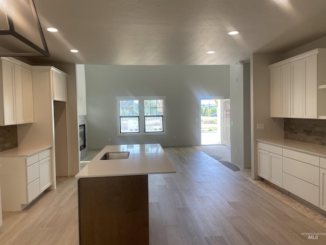 1640 E Cutgrass Ln, Eagle, ID 83616 - kitchen with decorative backsplash, a center island with sink, recessed lighting, light wood finished floors, and white cabinets