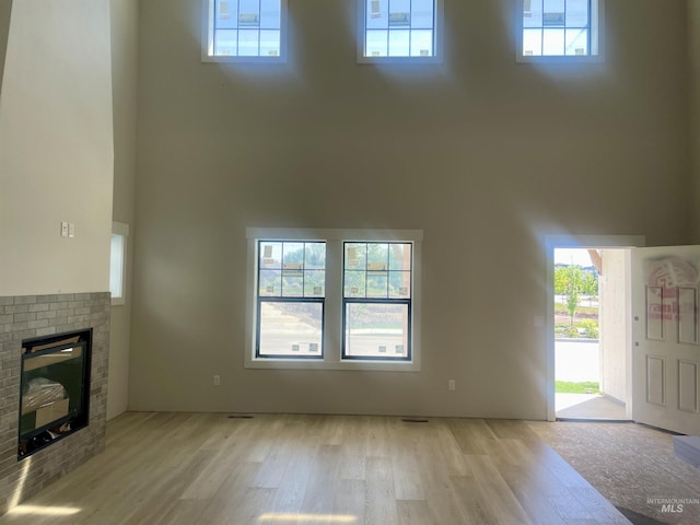 1640 E Cutgrass Ln, Eagle, ID 83616 - unfurnished living room with light wood-style flooring, a high ceiling, a brick fireplace, and healthy amount of natural light