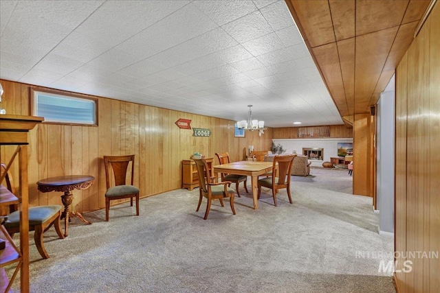 539 Rimview Dr, Twin Falls, ID 83301 - dining space featuring carpet flooring, a chandelier, wooden walls, and a brick fireplace