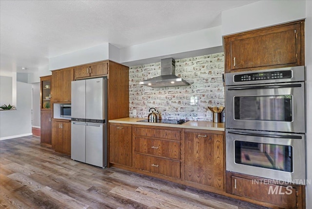 539 Rimview Dr, Twin Falls, ID 83301 - kitchen with appliances with stainless steel finishes, wall chimney range hood, wood finished floors, light countertops, and backsplash