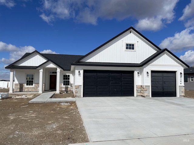 modern farmhouse featuring board and batten siding, concrete driveway, an attached garage, and stone siding