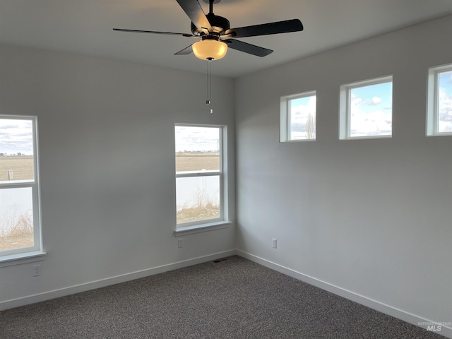 spare room featuring baseboards, ceiling fan, and dark carpet