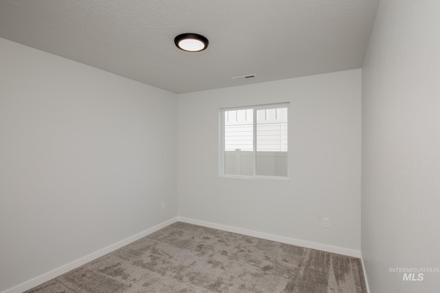 carpeted empty room with a textured ceiling and baseboards