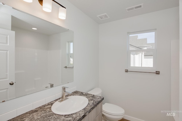 bathroom featuring toilet, vanity, and visible vents