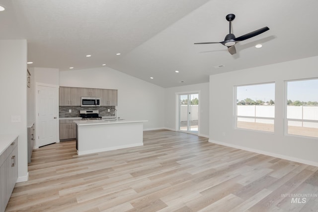 kitchen with decorative backsplash, open floor plan, light countertops, vaulted ceiling, and stainless steel appliances