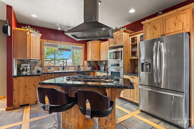 kitchen with a textured ceiling, appliances with stainless steel finishes, island exhaust hood, a center island, and sink