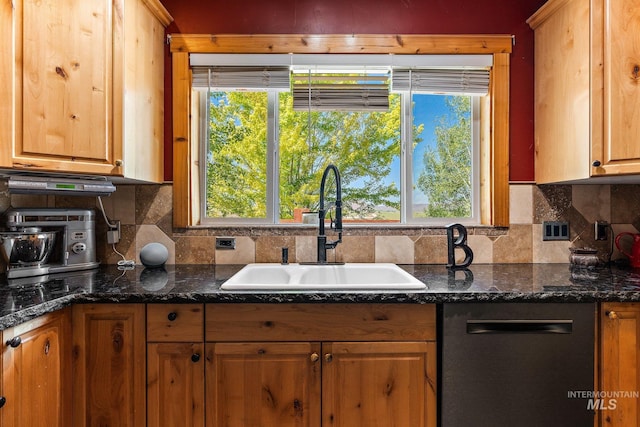 kitchen with decorative backsplash, dark stone counters, and sink