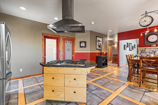 kitchen featuring tile patterned floors, stainless steel appliances, light brown cabinets, a kitchen bar, and island range hood