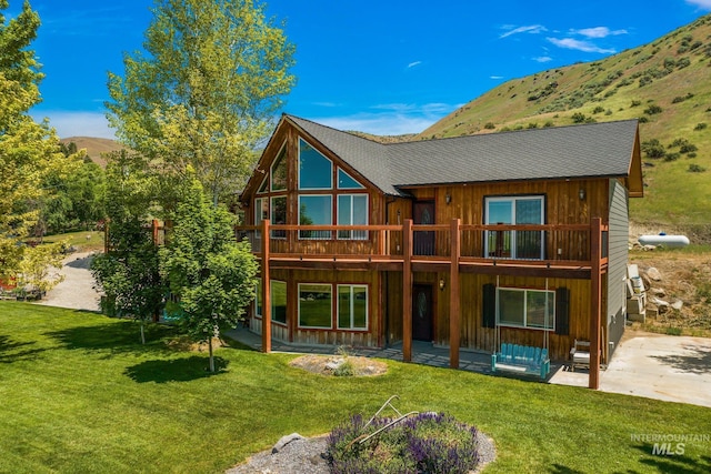 back of house with a yard, a mountain view, and a balcony