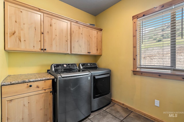 laundry room featuring washer and clothes dryer, cabinets, and tile patterned floors