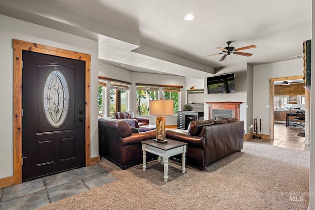 living room featuring a textured ceiling, ceiling fan, and light carpet