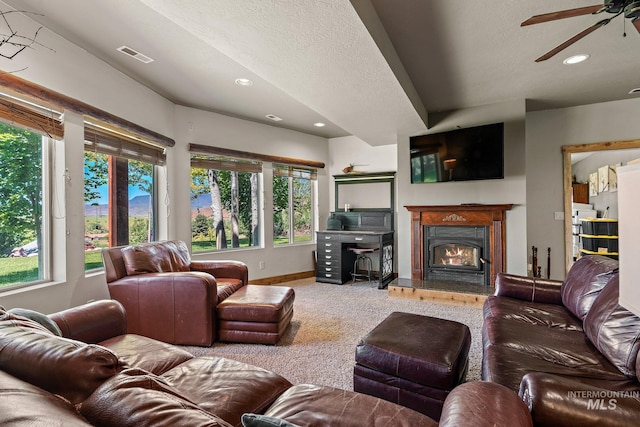 carpeted living room featuring ceiling fan, a textured ceiling, and a healthy amount of sunlight