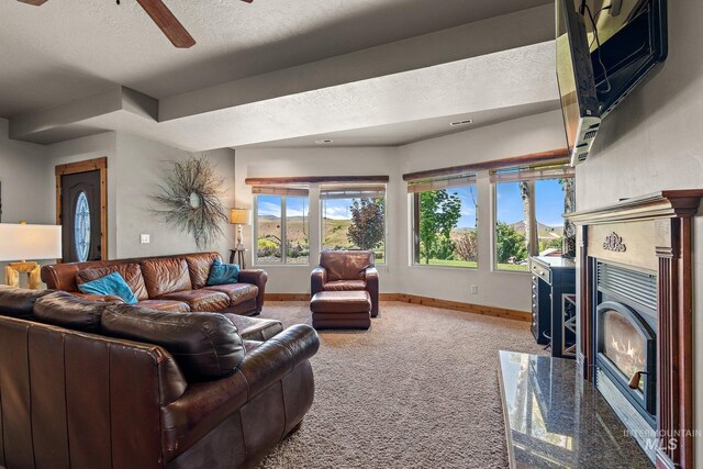 living room with a fireplace, a textured ceiling, plenty of natural light, and ceiling fan