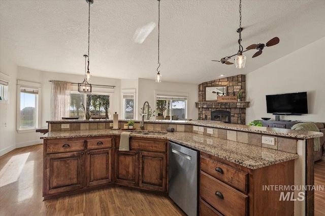 kitchen with wood finished floors, a textured ceiling, a sink, and dishwasher