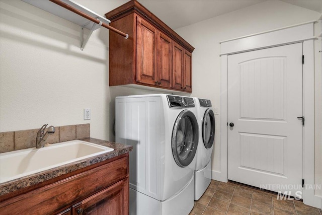 clothes washing area with independent washer and dryer, a sink, and cabinet space