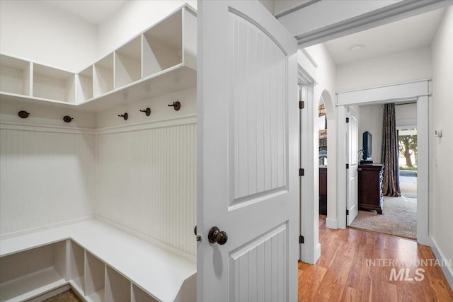 mudroom with light wood-style floors and arched walkways