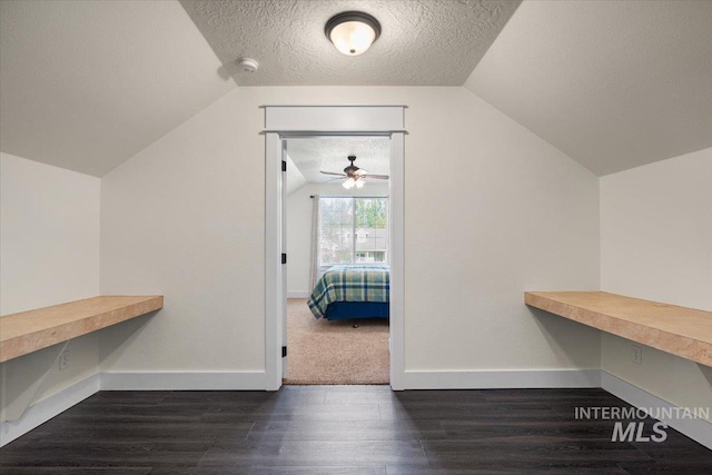 walk in closet featuring dark wood-style flooring, a ceiling fan, and vaulted ceiling