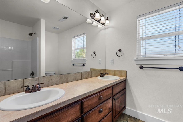 bathroom with a sink, walk in shower, and visible vents