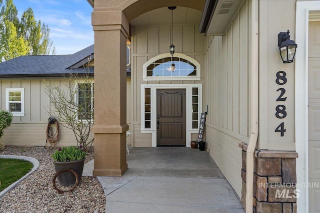 property entrance featuring a shingled roof, board and batten siding, and visible vents