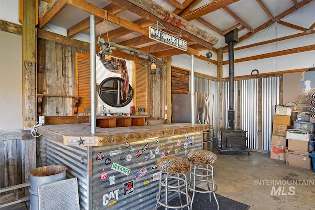 miscellaneous room with concrete flooring, a dry bar, and a wood stove
