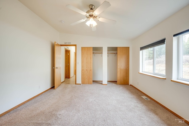 unfurnished bedroom with visible vents, light carpet, baseboards, and multiple closets