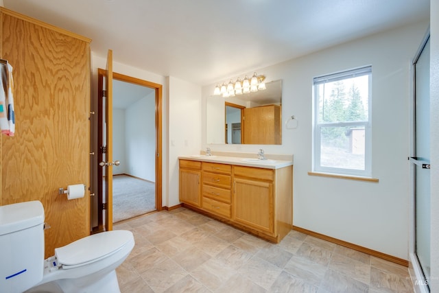 bathroom featuring double vanity, toilet, baseboards, and a sink