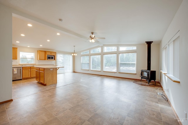 kitchen featuring a sink, lofted ceiling with beams, stainless steel appliances, light countertops, and a wood stove