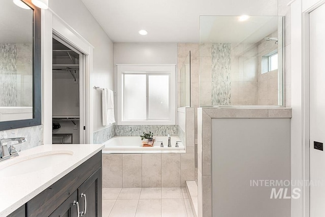 2251 N Garnet Creek Ave, Star, ID 83669 - bathroom featuring a garden tub, vanity, walk in shower, a spacious closet, and tile patterned floors
