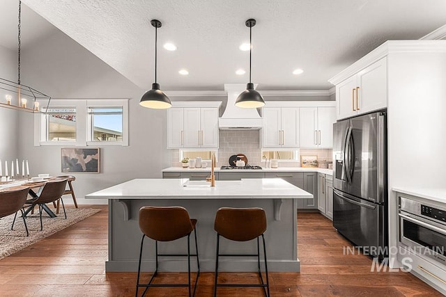 2251 N Garnet Creek Ave, Star, ID 83669 - kitchen with appliances with stainless steel finishes, custom range hood, light countertops, backsplash, and a breakfast bar