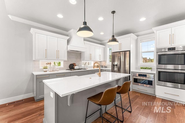 2251 N Garnet Creek Ave, Star, ID 83669 - kitchen with appliances with stainless steel finishes, custom exhaust hood, ornamental molding, a sink, and tasteful backsplash