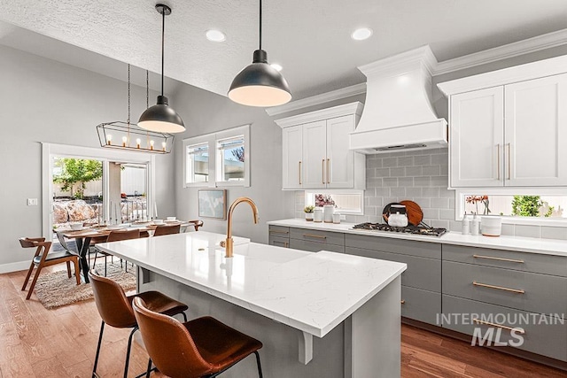 2251 N Garnet Creek Ave, Star, ID 83669 - kitchen with gray cabinets, premium range hood, a sink, stainless steel gas stovetop, and decorative backsplash