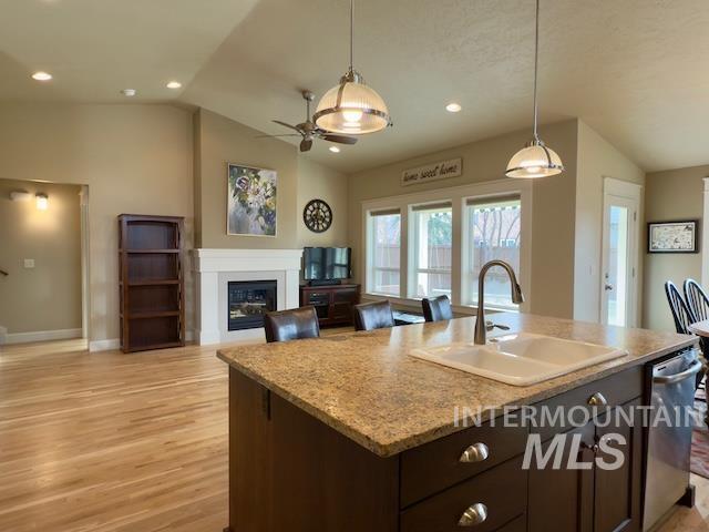 kitchen featuring dishwasher, lofted ceiling, sink, and a kitchen island with sink