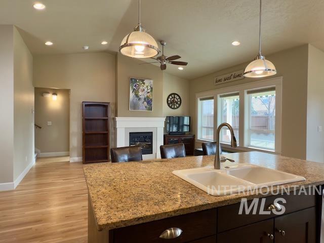 kitchen with sink, decorative light fixtures, vaulted ceiling, and an island with sink