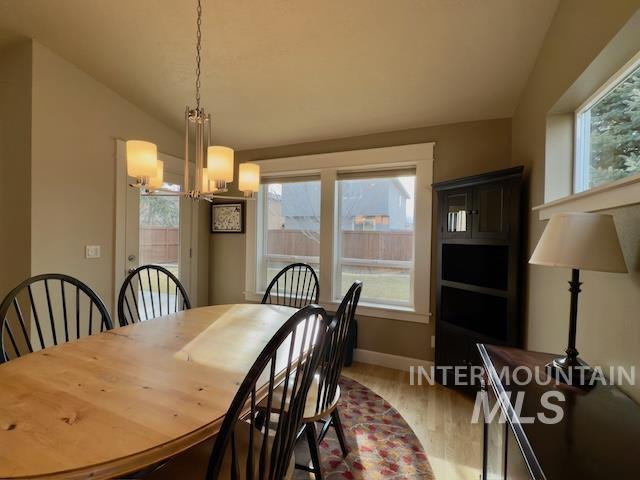 dining area featuring vaulted ceiling, wood-type flooring, and a chandelier