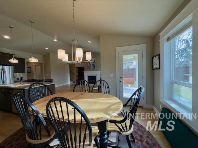 dining space with plenty of natural light, sink, a chandelier, and vaulted ceiling