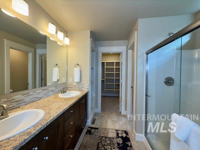 bathroom featuring vanity, backsplash, and a shower with shower door