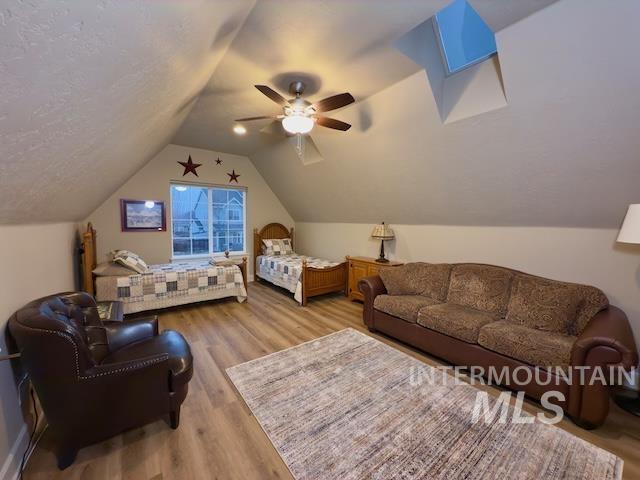 bedroom featuring ceiling fan, light hardwood / wood-style flooring, a textured ceiling, and vaulted ceiling